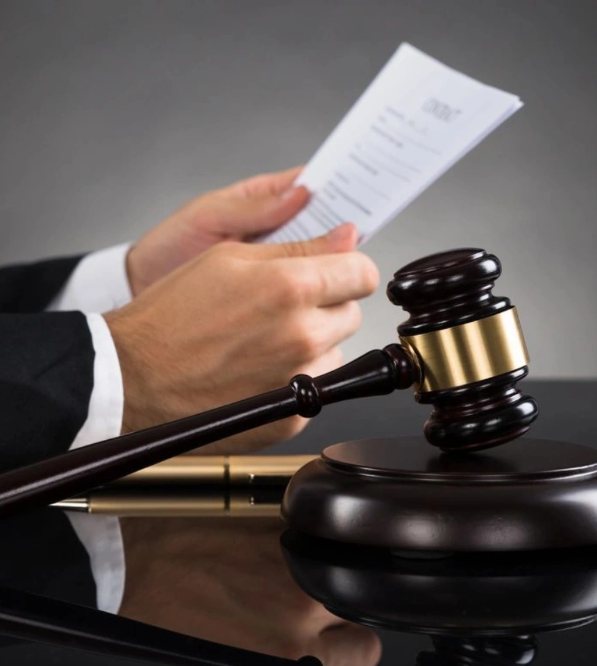 A judge holding papers and gavel on top of desk.