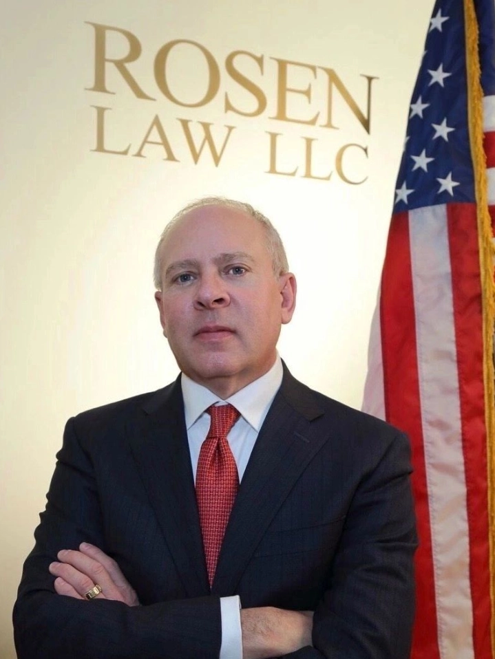 A man in suit and tie standing next to an american flag.