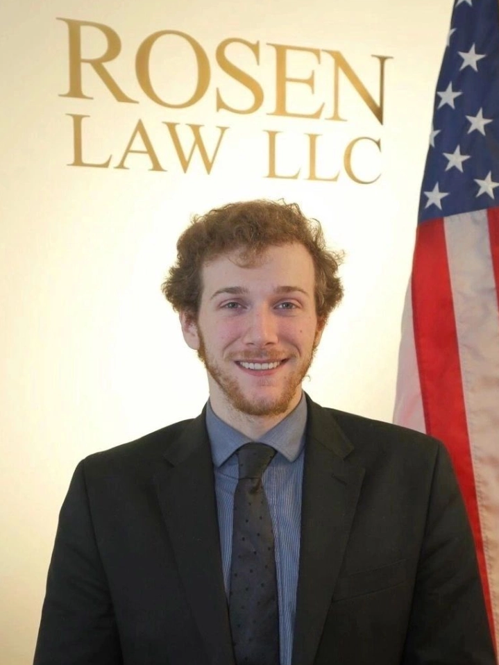 A man in suit and tie standing next to an american flag.