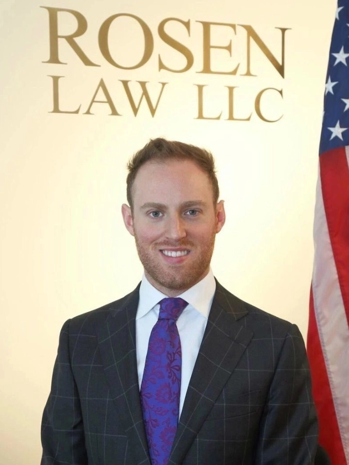 A man in suit and tie standing next to an american flag.