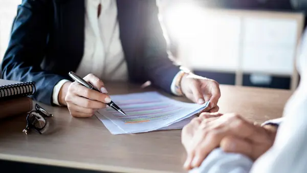 Person pointing at highlighted document in meeting
